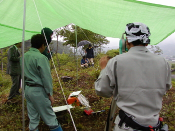 テントの中から測量機器を使っての測量作業（南から）の写真